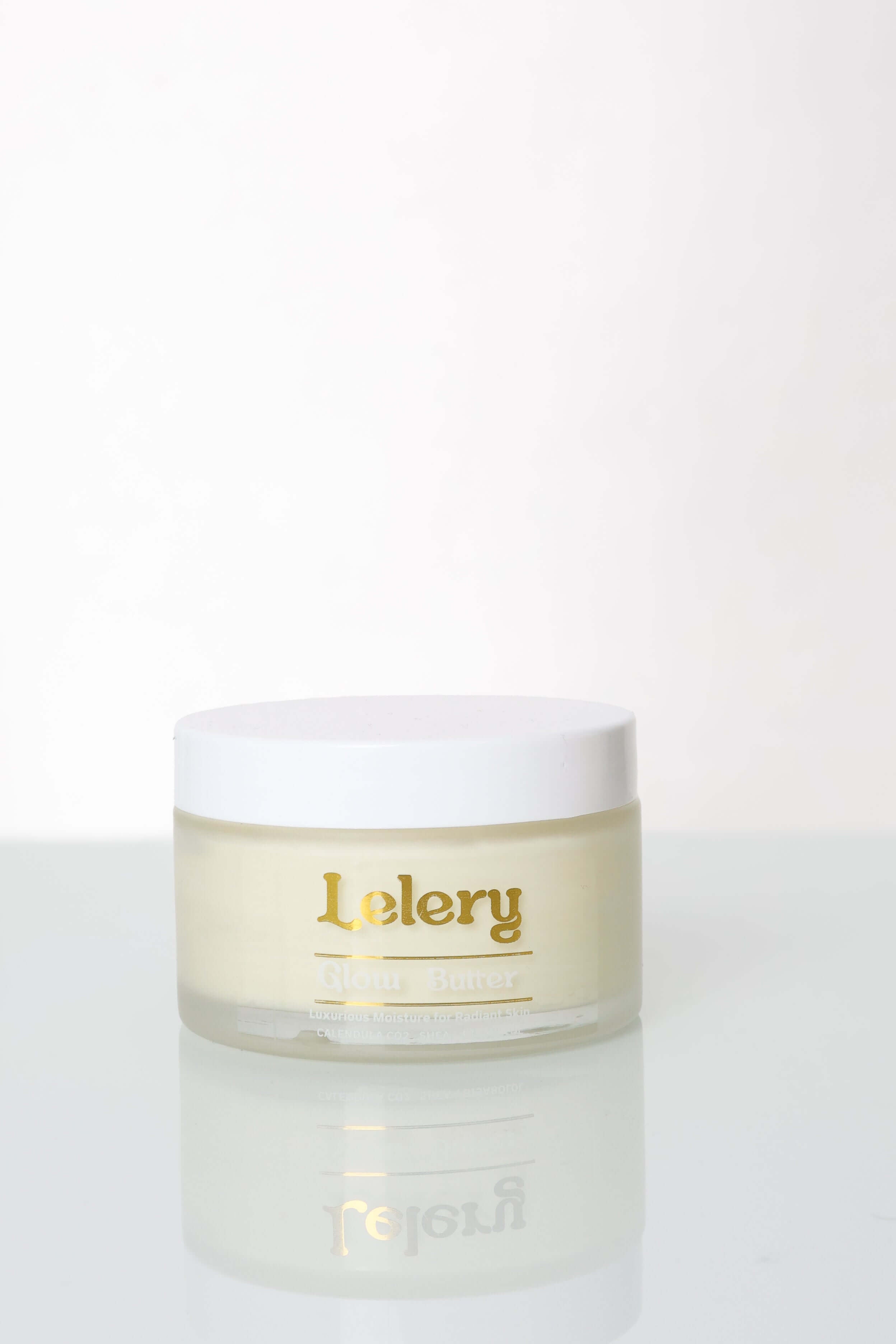 Whipped Body Butter for Glowing Skin in a stylish jar with a gold label on a reflective surface.